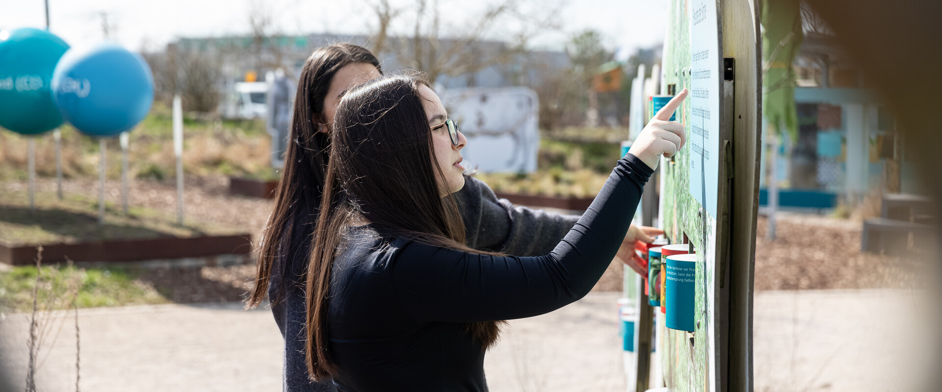 Sch&uuml;lerinnen schauen sich Ausstellungsstation im Au&szlig;enbereich der KLIMA ARENA an.